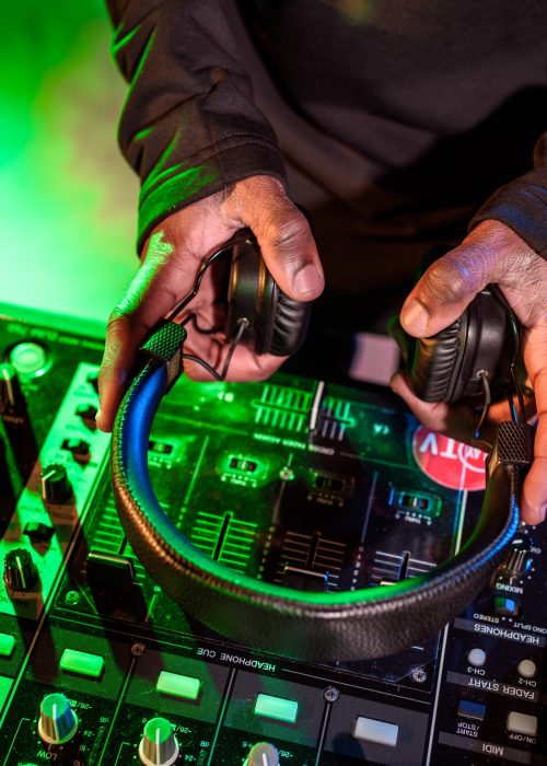 cropped view of DJ hands holding headphones over sound mixer cropped view of DJ hands holding headphones over sound mixer