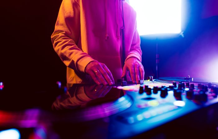 Hands of a DJ creating and regulating music on dj console mixer at club concert